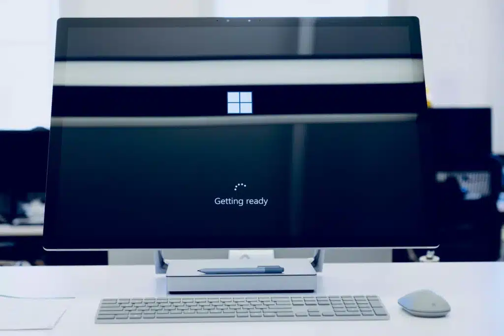 Microsoft loading screen on wide black computer monitor with grey keyboard and mouse