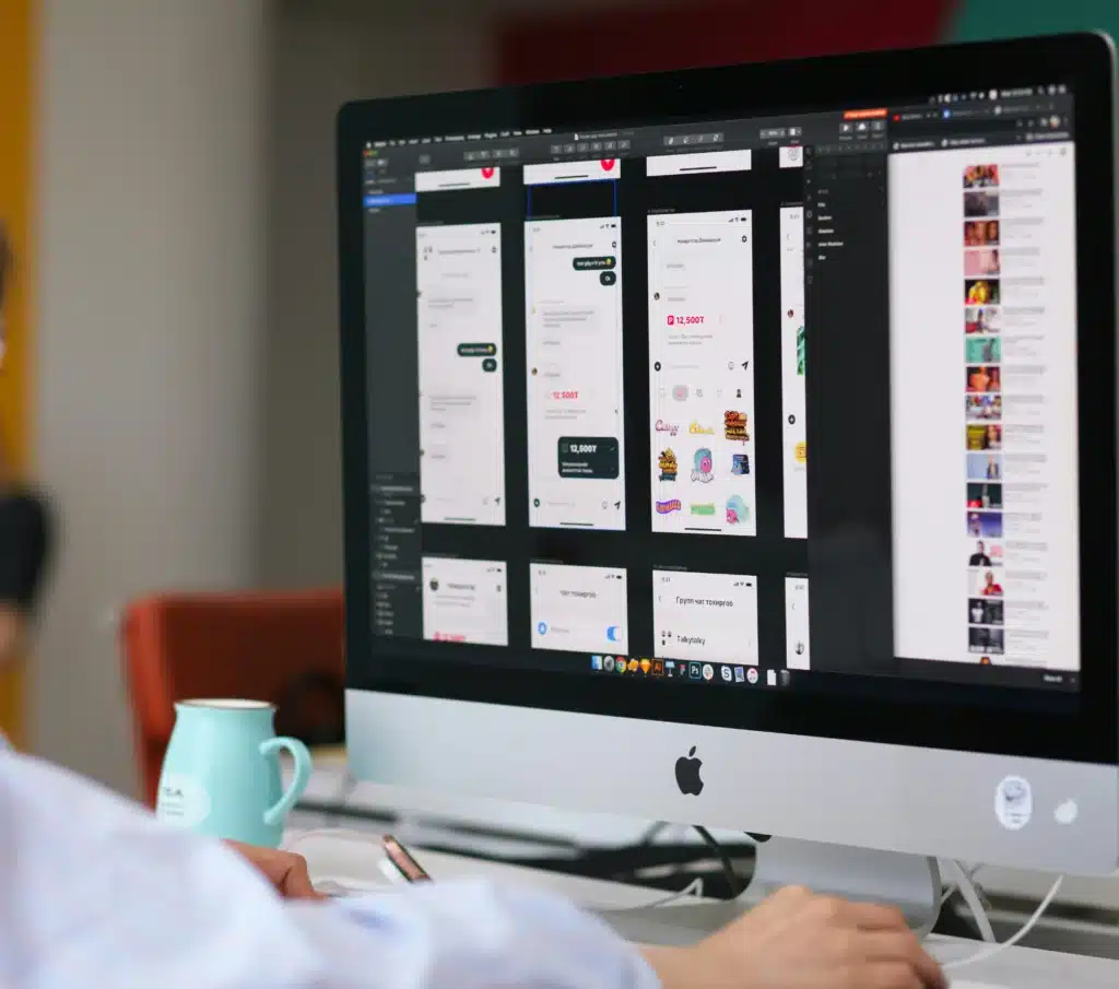 Back of person working on iMac with Adobe Illustrator open on screen
