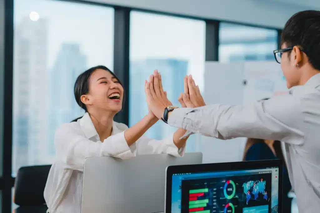 Man and woman high fiving over iMacs at the office