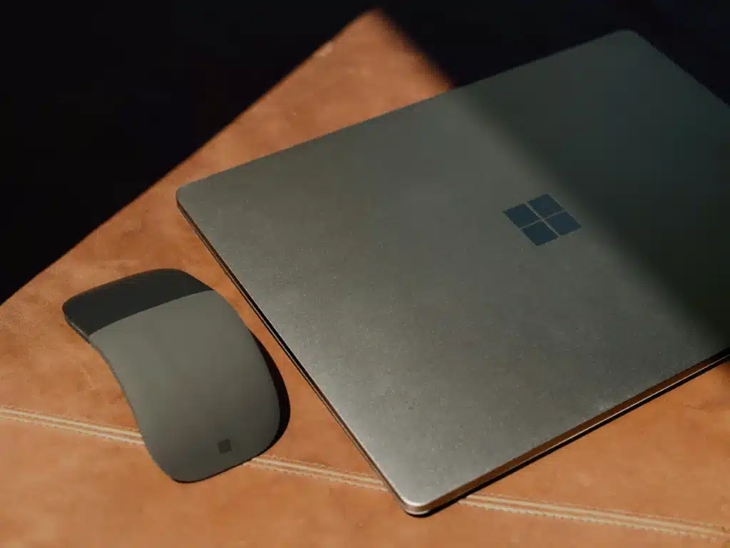 Photo of a Microsoft Surface laptop and mouse on a brown leather chair