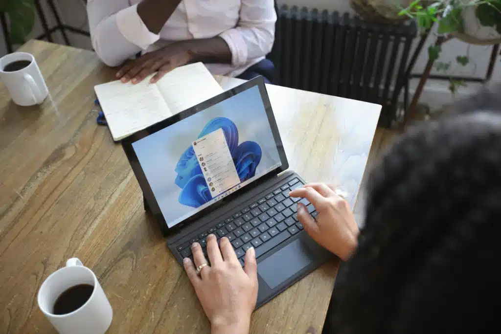 Woman typing on Microsoft Surface while facing co worker at table
